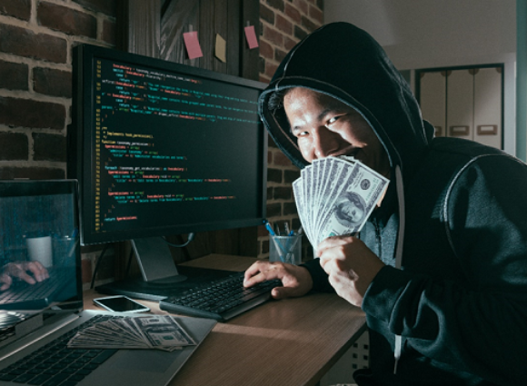 Man Showing Cash In His Hands Working On A Computer