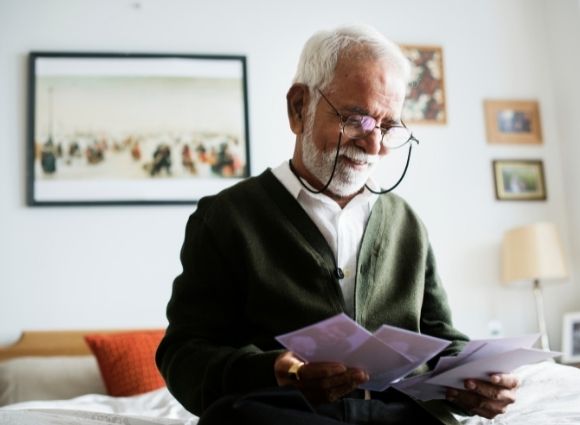 Elder Man Looking At Pamphlets At Home