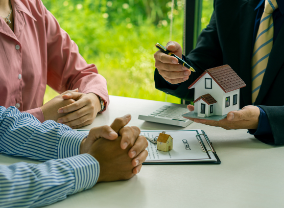 Photo Of A Couple Sitting At A Table With A Realtor Giving Them A House