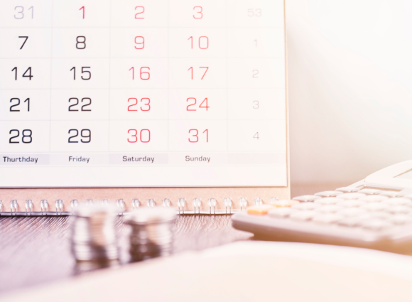 Photo Of A Calendar With Coins And A Calculator In Front