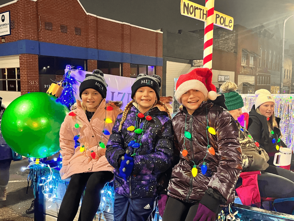 Three Children Sitting On The North Pole Float Smiling
