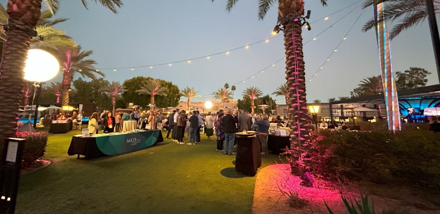 Photo of the Spire Lawn at the Arizona Biltmore featuring palm trees, big lights, and people conversing around tables